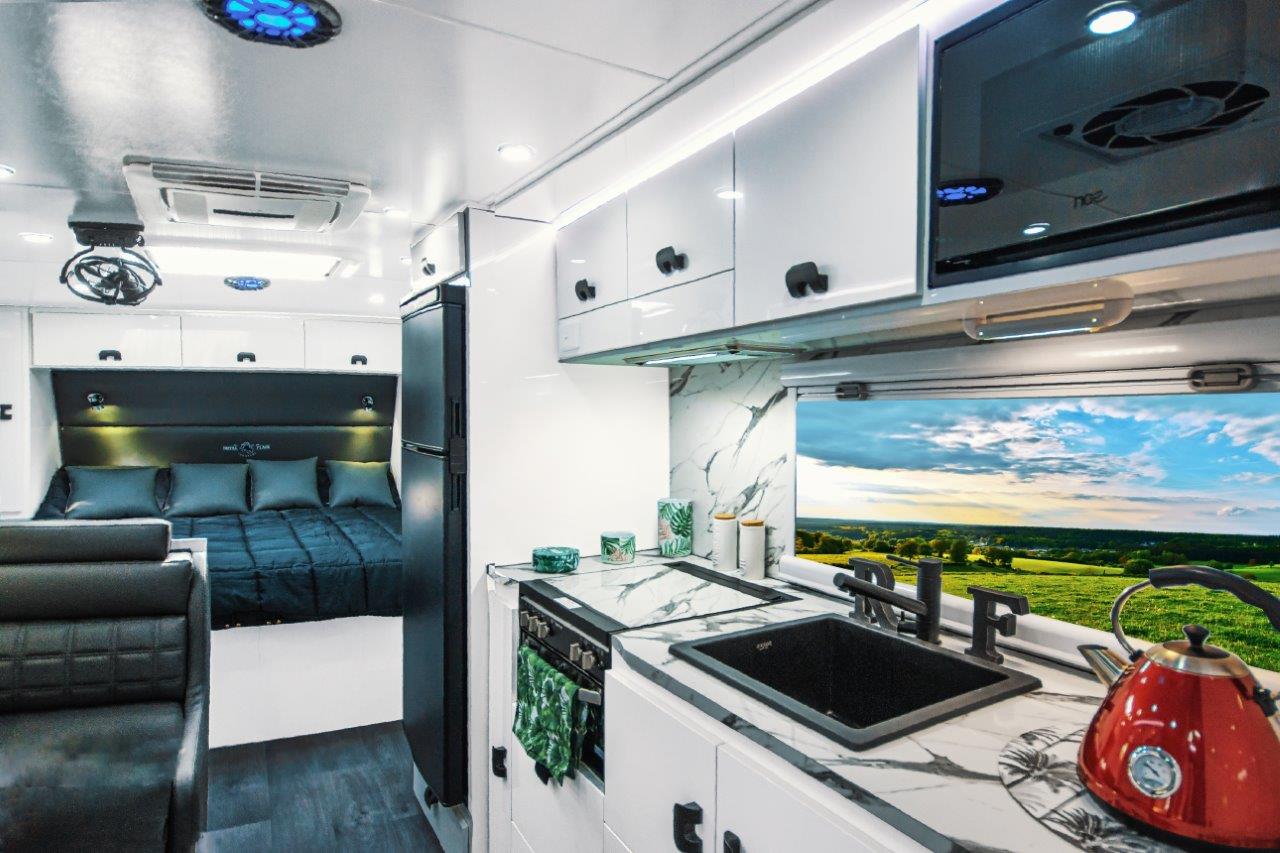 Interior of an Aussiemate caravan with cozy kitchen seating, natural light, and integrated storage