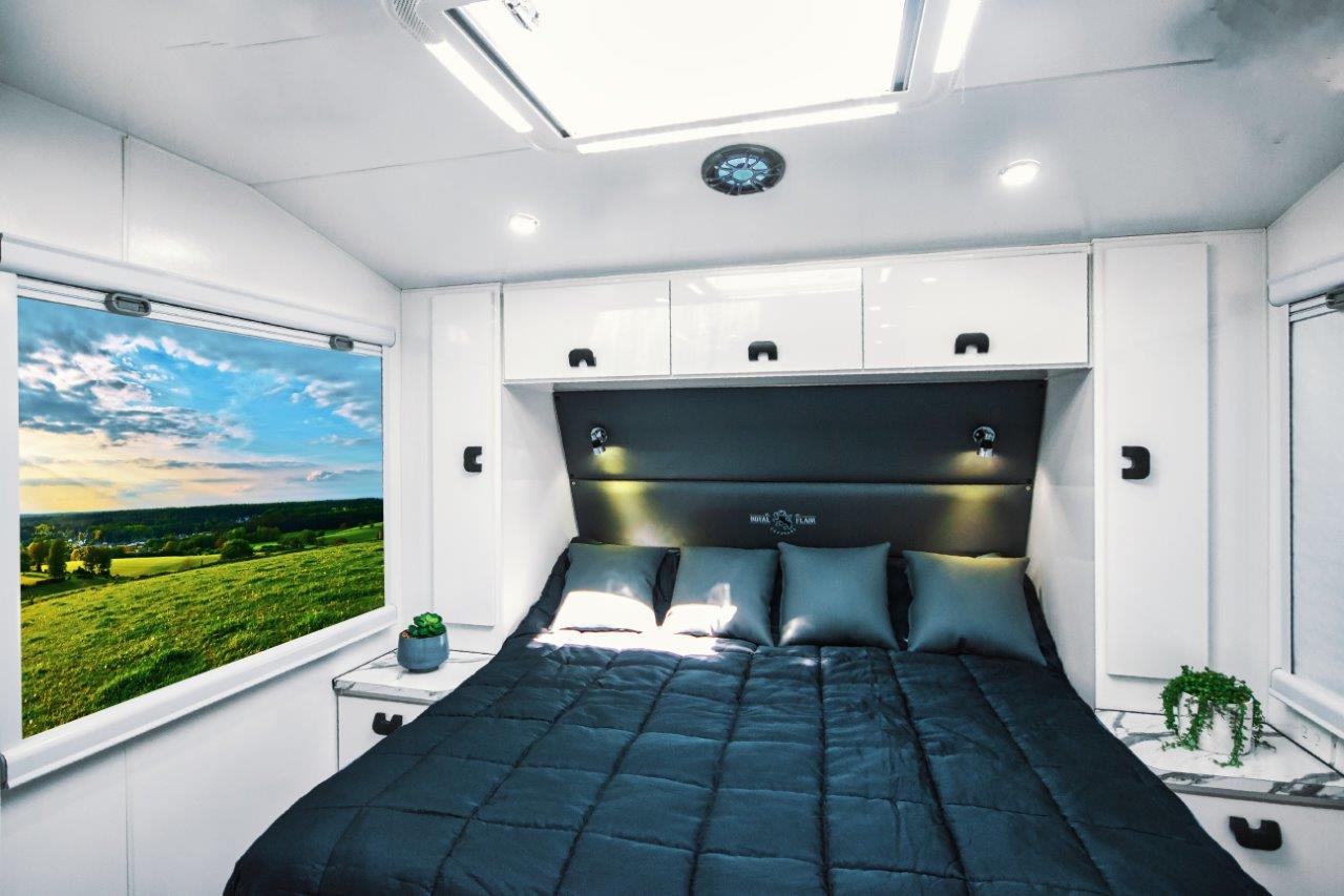 Interior of an Aussiemate caravan with cozy bed, natural light, and integrated storage