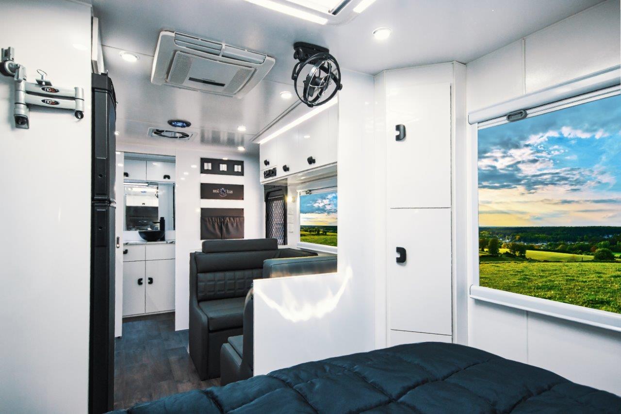 Interior of an Aussiemate caravan with cozy lounge seating, natural light, and integrated storage